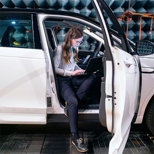 E_Auto_Ingenieurin_mit_Laptop_im_Auto